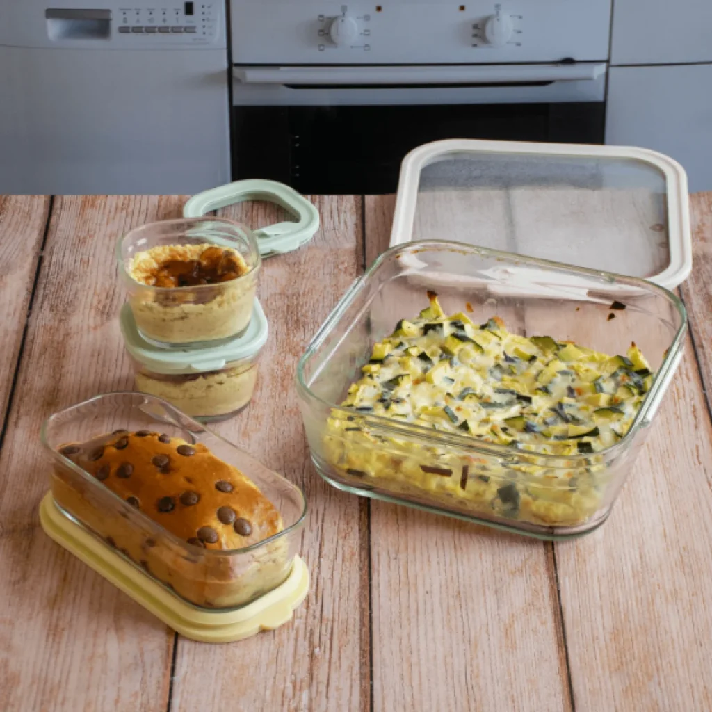 taperes de vidrio pebbly con hummus bizcocho y verduras gratinadas sobre una mesa de madera