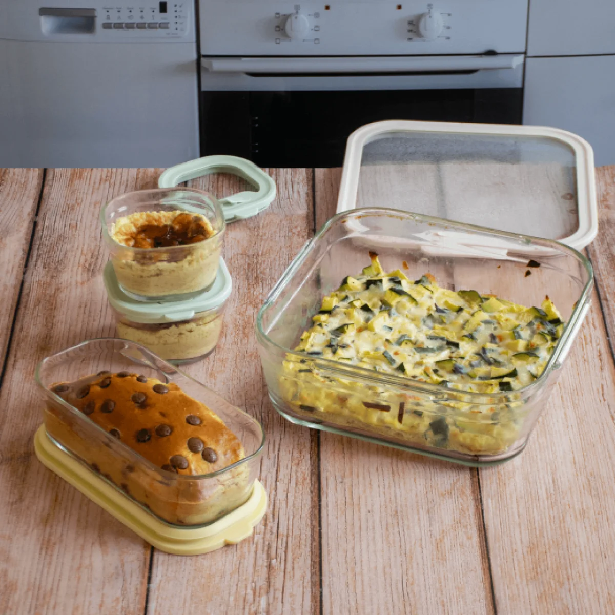 taperes de vidrio pebbly con hummus bizcocho y verduras gratinadas sobre una mesa de madera