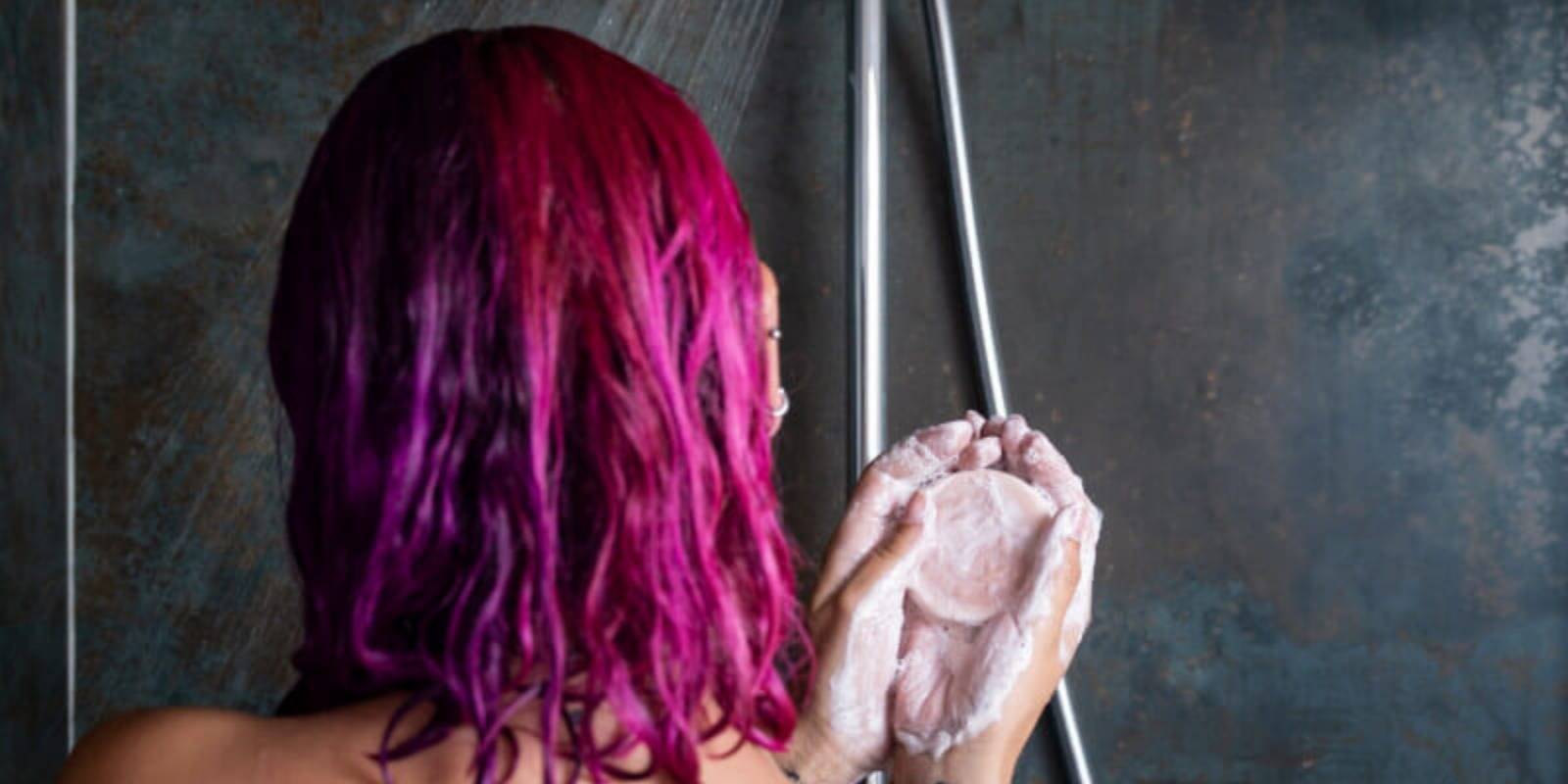 Mujer con cabello teñido y champú sólido en sus manos