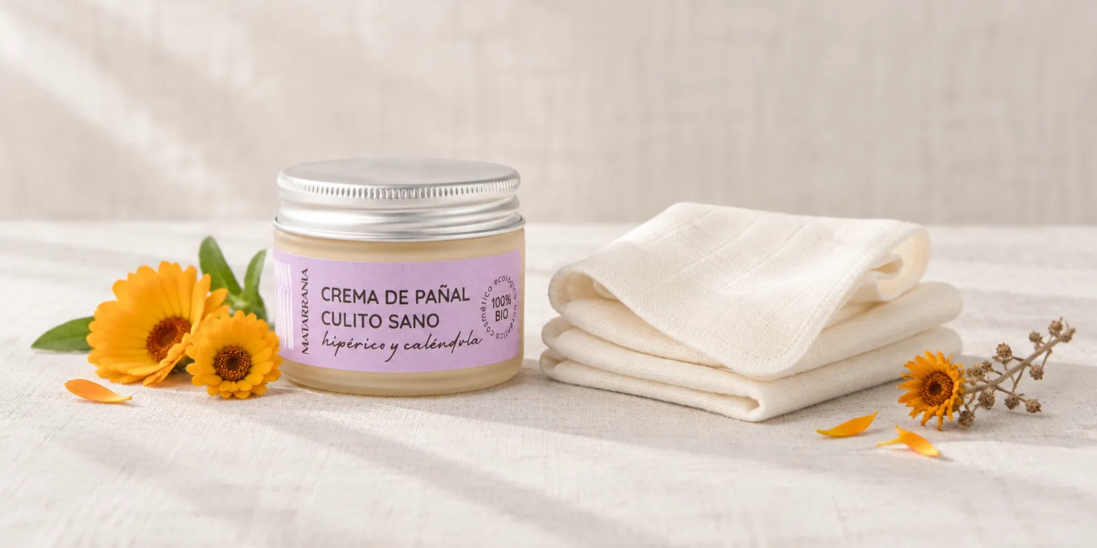 Crema de pañal ecológica sin fragancia junto a toallitas reutilizables de algodón orgánico sobre lino crudo