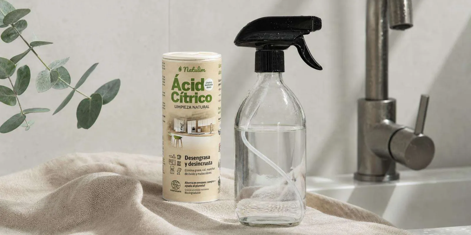 Ácido cítrico en polvo y botella de vidrio con pulverizador sobre encimera de baño para quitar la cal de los grifos