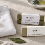 Camisa blanca con una mancha de aceite junto a dos pastillas de jabón quitamanchas sobre lino crudo