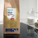 Vitrocerámica negra impecable junto a un tarro de bicarbonato y un paño de lino en una cocina serena