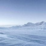 Paisaje de la Antártida: extenso campo de hielo y nieve prístina bajo luz fría, con montañas nevadas al fondo