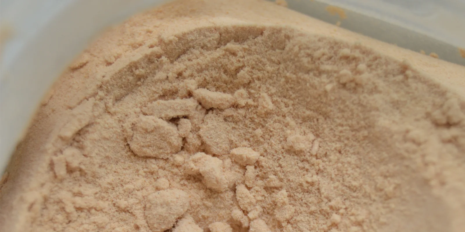 Primer plano de un polvo fino de color melocotón, obtenido de las nueces de lavado, en un recipiente